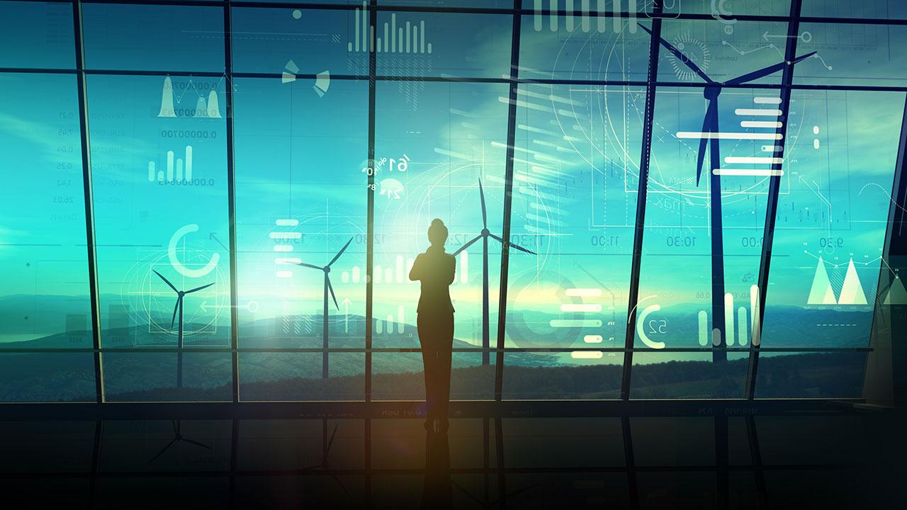 Woman in silhouette in control room of wind farm with data elements pictured against the window