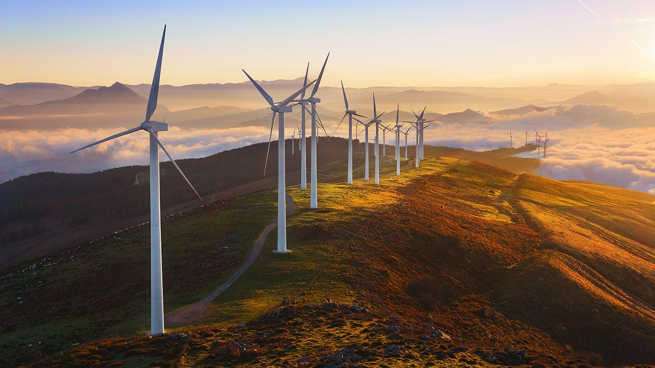 Wind turbines lined up on top of a mountain at sunrise